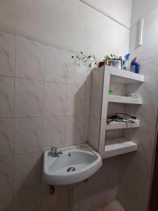 a bathroom with a sink in a white tiled wall at The Gardenview in Guwahati
