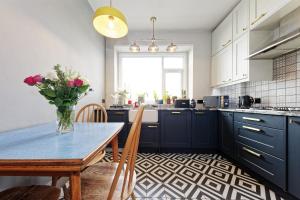 a kitchen with blue cabinets and a table with a vase of flowers at Walpole Bay Sea Views in Margate