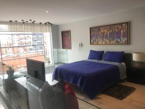 um quarto com uma cama azul e uma televisão em Quito,lofth of Luxe en la Finlandia em Quito