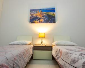 - une chambre avec 2 lits et une photo sur le mur dans l'établissement Sea View Over Valletta Strand Area, à Sliema