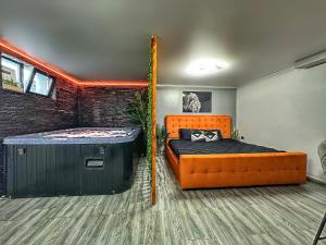 1 dormitorio con cama naranja y bañera grande en Luxor - Jacuzzi&Cozy Apartments, en Sibiu