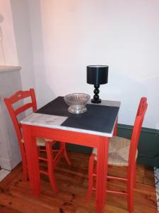 - une table rouge avec deux chaises et un bol sur le dessus dans l'établissement Chez Frida, au Puy-en-Velay