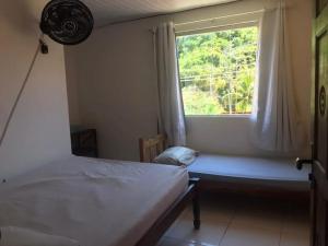 um quarto com uma janela com uma cama e um assento na janela em Pousada Guest House Rota 027 Morro de São Paulo em Morro de São Paulo