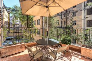 eine Terrasse mit einem Tisch, Stühlen und einem Sonnenschirm in der Unterkunft Via Napoli Apartments in Rom