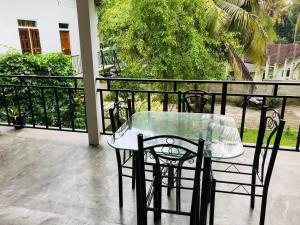 uma mesa de vidro e cadeiras numa varanda em Midira Villa em Galle