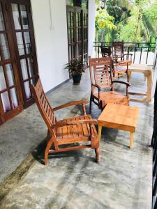 a group of wooden chairs and a table on a porch at Midira Villa in Galle