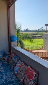 a balcony with pillows and a view of a field at Yasmine Guest House in Luxor