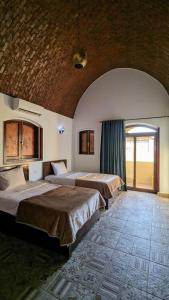 two beds in a large room with a large window at Yasmine Guest House in Luxor