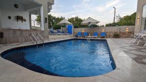 une piscine avec des chaises bleues et une maison dans l'établissement Yasmine Guest House, à Louxor