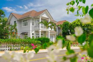 ein großes weißes Haus mit einem Zaun und Blumen in der Unterkunft Casa Villa - Floral Park- Sealinks City Resort in Phan Thiet