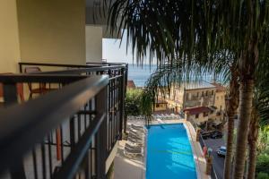 a balcony with a palm tree and a swimming pool at Hotel Corallo in Taormina