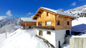 een houten huis bovenop een met sneeuw bedekte berg bij Bright & elegant stand alone chalet - 8 ppl - Vois Le Mont in Les Gets