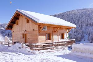 a wooden cabin in the snow with snow at Vois le Mont in Les Gets