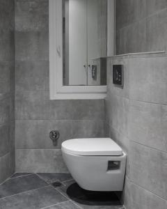 uma casa de banho com um WC branco e um espelho. em Your Cosy Perch in the Heart of the Athenian Buzz em Atenas