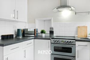 a kitchen with white cabinets and a stove top oven at Gorgeous 4-bed Home in Nottingham by Renzo, Free Driveway Parking, Sleeps 7! in Beeston