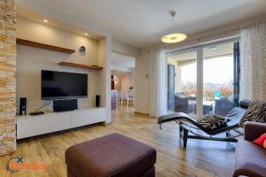 a living room with a flat screen tv and a couch at New villa with swimming pool, olive grove and sea view by Traveler tourist agency Krk ID 2201 in Brzac