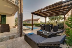 a patio with wicker furniture and a pergola at New villa with swimming pool, olive grove and sea view by Traveler tourist agency Krk ID 2201 in Brzac