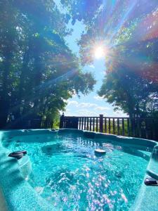 a swimming pool with the sun shining through trees at Fieldfare Lodge with Hot-tub in Carlisle