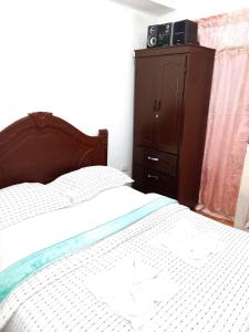 a bedroom with a bed and a dresser with a television on it at Hostal Posada Del Corazón in Salento