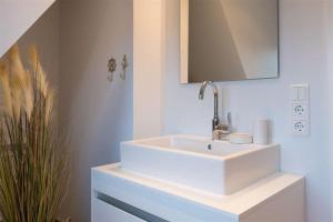een badkamer met een witte wastafel en een spiegel bij Robbenloft-Wohnung-11 in Keitum