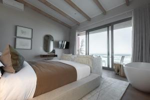 a bedroom with a large bed and a large window at Escape to the Beach in Wilderness