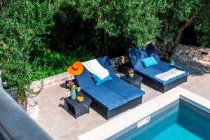 two blue couches sitting next to a swimming pool at Marceline in Prvić Luka