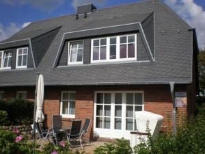 a house with two chairs and an umbrella in front of it at Haus-Gotland-Wohnung-10 in Westerland