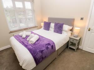 Un dormitorio con una cama grande con sábanas y almohadas púrpuras. en Hazel Cottage, en Keighley