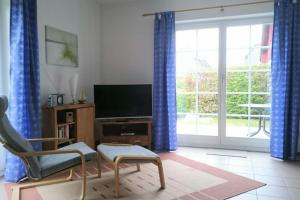 uma sala de estar com televisão e cortinas azuis em FeWo Ostseerose - DHH 4 em Prerow