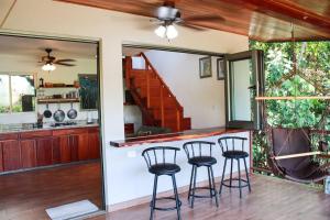 a kitchen with three bar stools in a kitchen with a staircase at Casita Colibri–Mile to the Beach–Cable&Fiber Wifi! in Uvita +18 photos