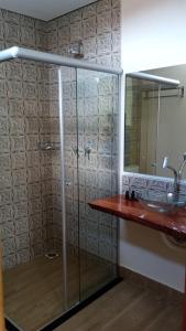 a bathroom with a shower with a sink and a mirror at Pousada São José na Canastra in Delfinópolis