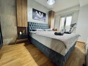 een slaapkamer met een groot bed met een blauw hoofdeinde bij Monika's Apartment in Skopje