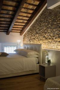 1 dormitorio con cama blanca y pared de piedra en Affittacamere CASA DOLCE CASA SAN DANIELE, en San Daniele del Friuli