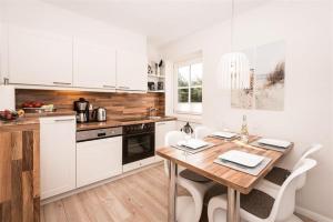 a kitchen with a wooden table and white cabinets at Tunghoern-Hues-1-OG-Wohnung-03 in Keitum