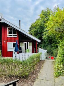 una casa roja con una valla blanca delante de ella en Extertal-Ferienpark - Premium Ferienhaus Sonnental - Sauna #50, en Extertal
