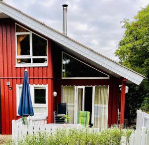 a red house with a white fence and an umbrella at Extertal-Ferienpark - Premium Ferienhaus Sonnental - Sauna #50 in Extertal