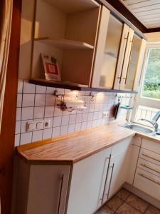 una pequeña cocina con fregadero y armarios blancos en Extertal-Ferienpark - Premium Ferienhaus Sonnental - Sauna #50, en Extertal