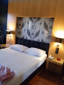 Olympic Hotel في بيرايوس: غرفة نوم بسرير كبير مع لوحة للرأس