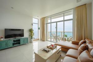 uma sala de estar com um sofá e uma televisão em Casa Home - Ocean Melody - Beach Front 3br Apartment em Phan Thiet