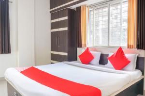Un dormitorio con una cama con almohadas rojas y una ventana en The Guest house, en Pune