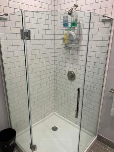 ducha con puerta de cristal y azulejos blancos en RobbinsStreetWaltham, en Waltham