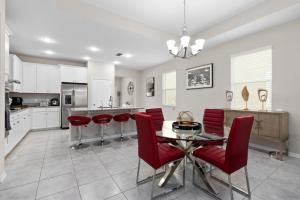 a kitchen with a dining table and red chairs at Luxurious Tampa Bay Area Home in Serene Community! in Riverview