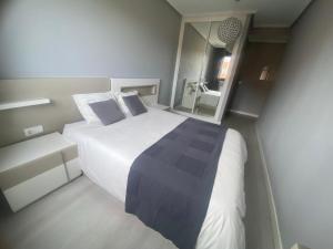 ein Schlafzimmer mit einem großen weißen Bett und einem Spiegel in der Unterkunft Casa cerca de la playa in Urduliz