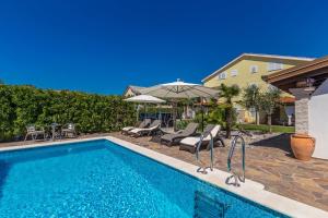 a swimming pool with chairs and an umbrella at Guest House Antonella in Malinska
