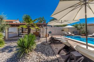 a backyard with a swimming pool and an umbrella at Guest House Antonella in Malinska