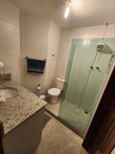 a bathroom with a toilet and a glass shower at Guaiuba's House in Guarujá