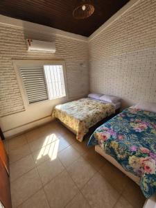 a bedroom with two beds and a window at Guaiuba's House in Guarujá