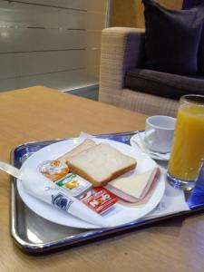 einen Teller mit einem Sandwich und einem Glas Orangensaft in der Unterkunft Olympic Hotel in Piräus