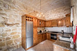 a kitchen with wooden cabinets and a stainless steel refrigerator at 4 Bedroom Farmhouse with Large Private Pool in Xewkija