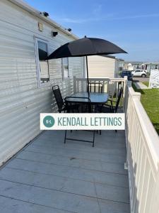 a patio with a table and an umbrella at Oakley (West Sands) in Selsey